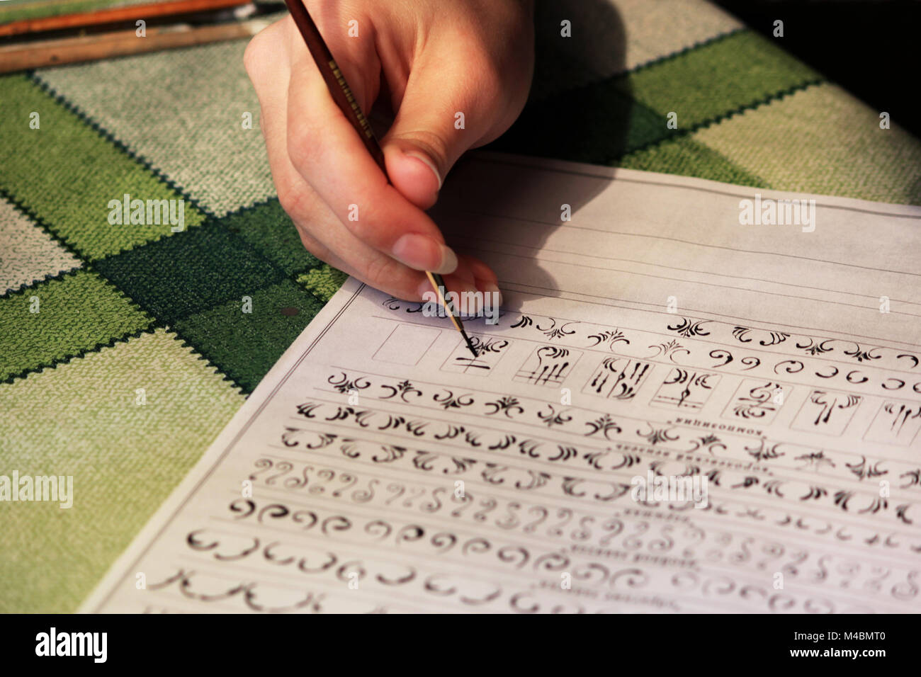 Una studentessa impara a disegnare monogrammi per li disegno sulle unghie durante la creazione di una manicure con lacca shellac. acrilico vernice nero, foglio di formazione Foto Stock