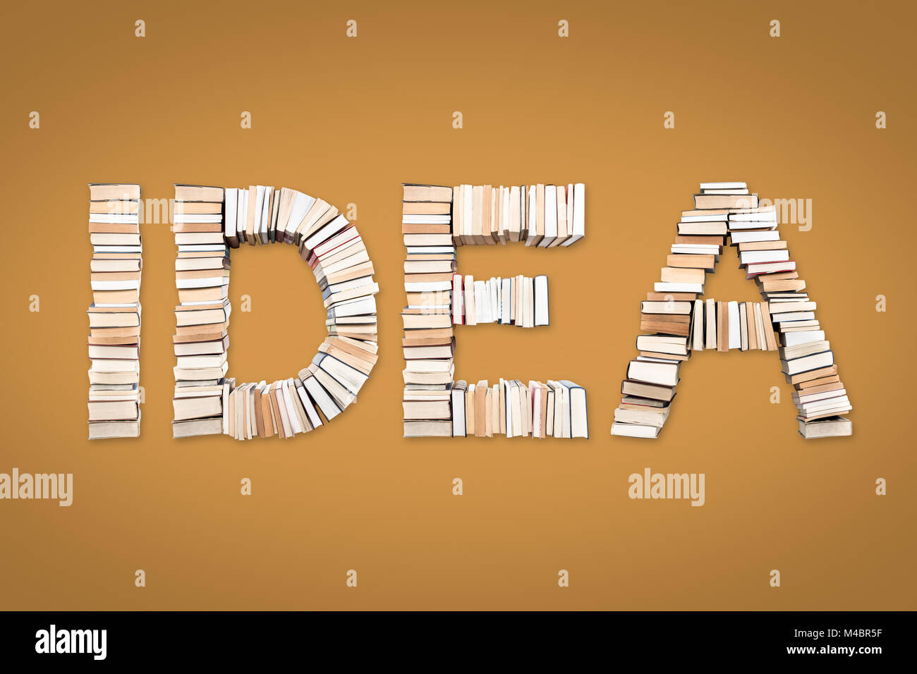 IDEA parola formata da libri, ripresa dall'alto su sfondo giallo Foto Stock
