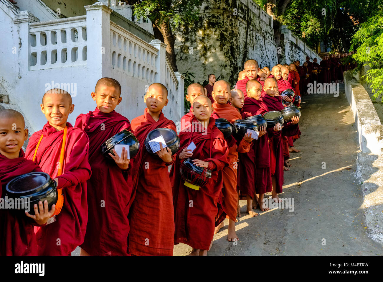 I monaci buddisti sono in coda in una lunga fila per ricevere donazioni in un monastero Foto Stock