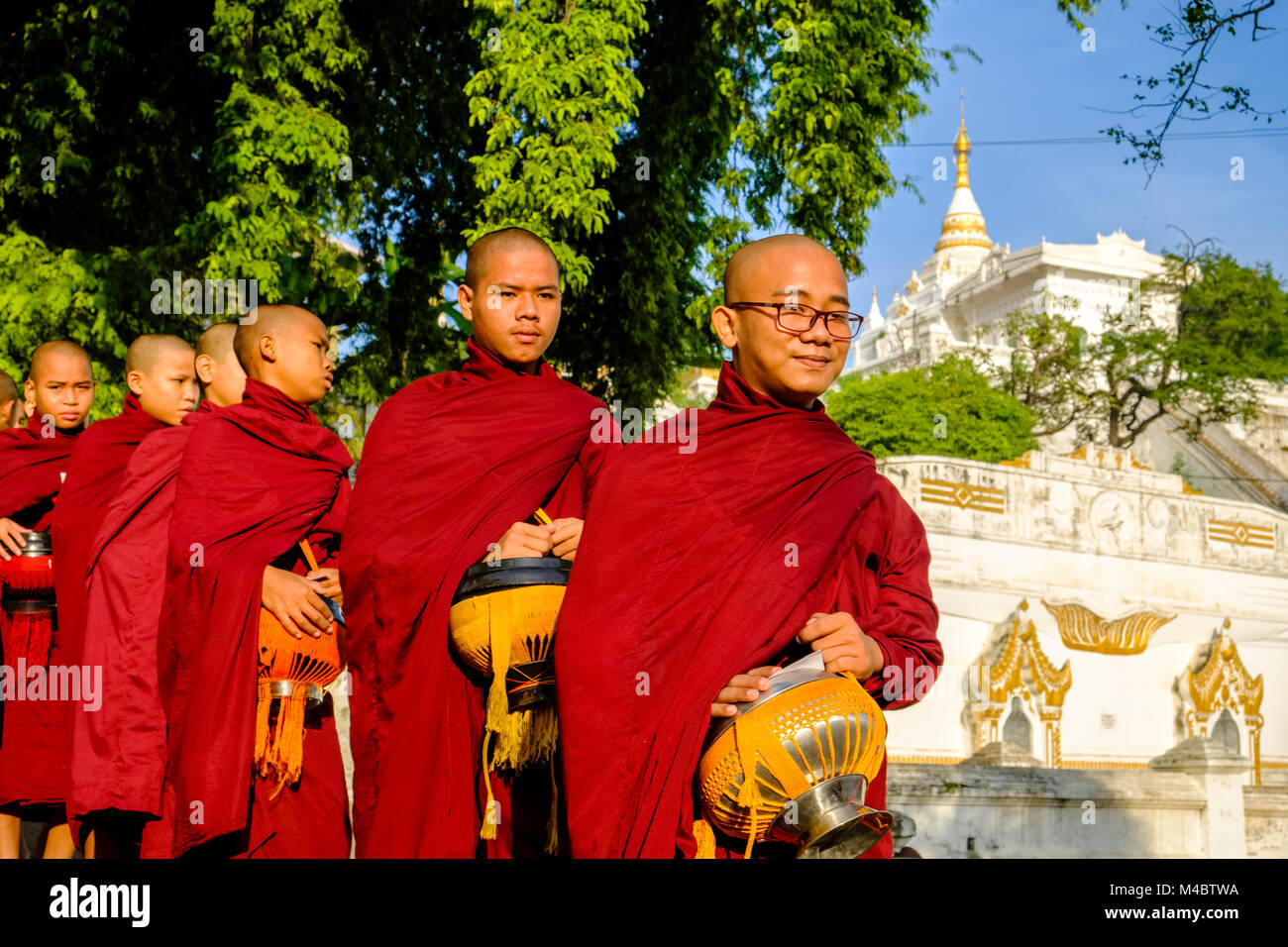 I monaci buddisti sono in coda in una lunga fila per ricevere donazioni in un monastero Foto Stock