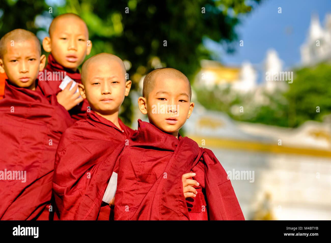 Ritratti di giovani monaci buddisti in coda in una lunga fila per ricevere donazioni in un monastero Foto Stock