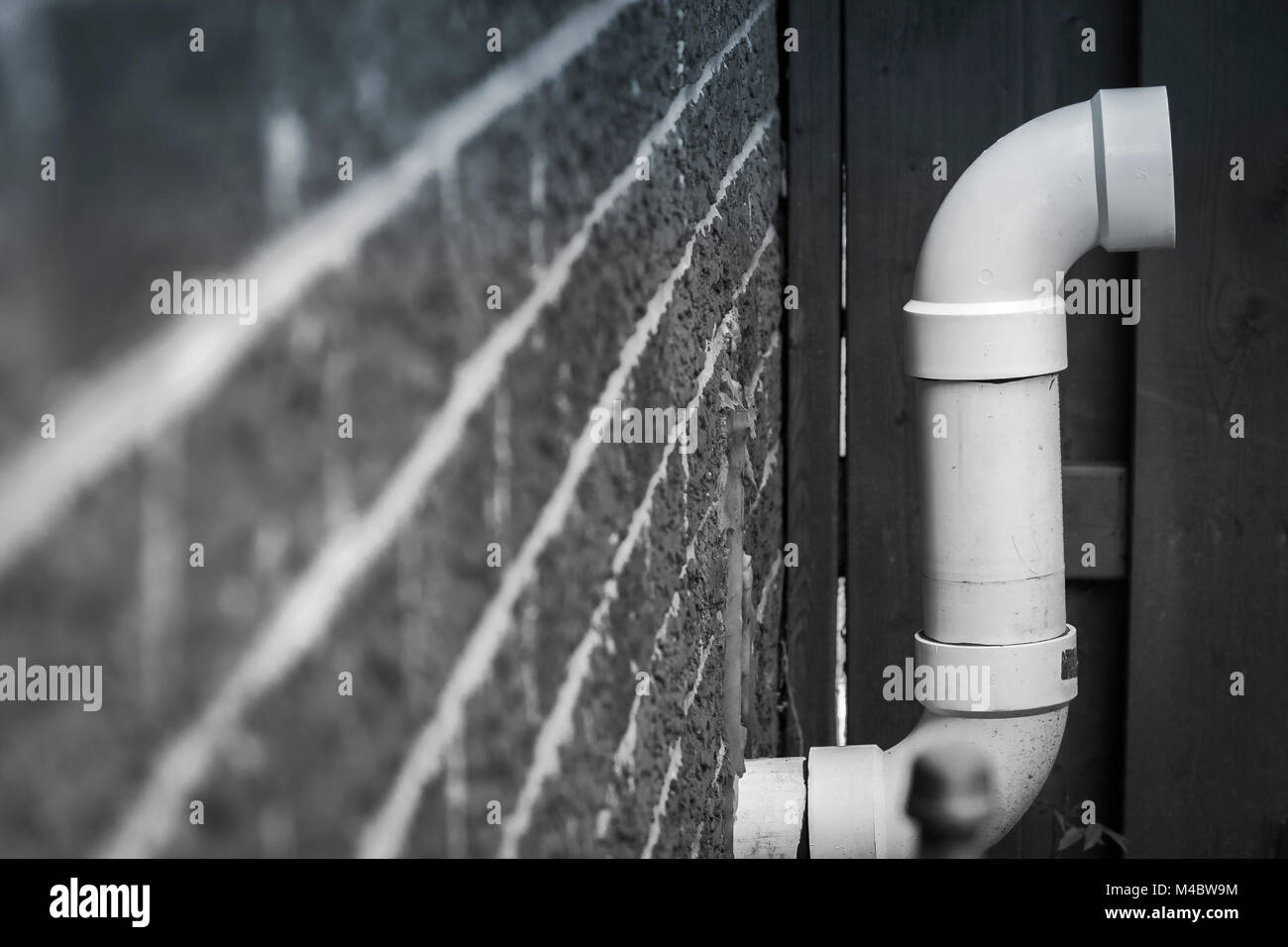 Un PVC bianco forno tubo di scarico esce da un muro di mattoni Foto Stock