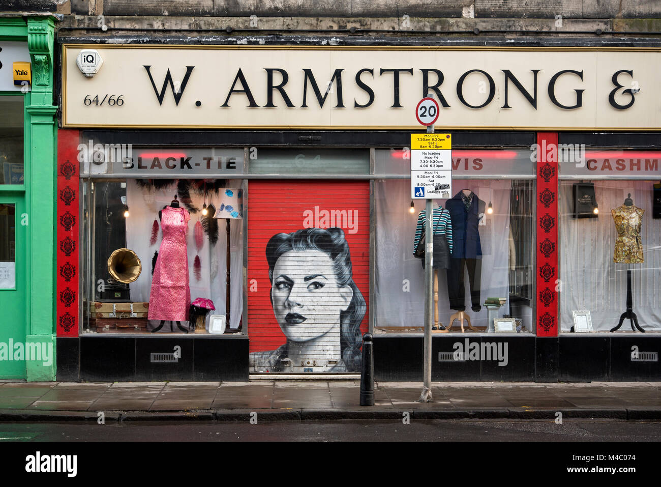 Vintage Armstrongs negozio di abbigliamento con la saracinesca giù rivelando un protrait retrò di una giovane donna. Foto Stock