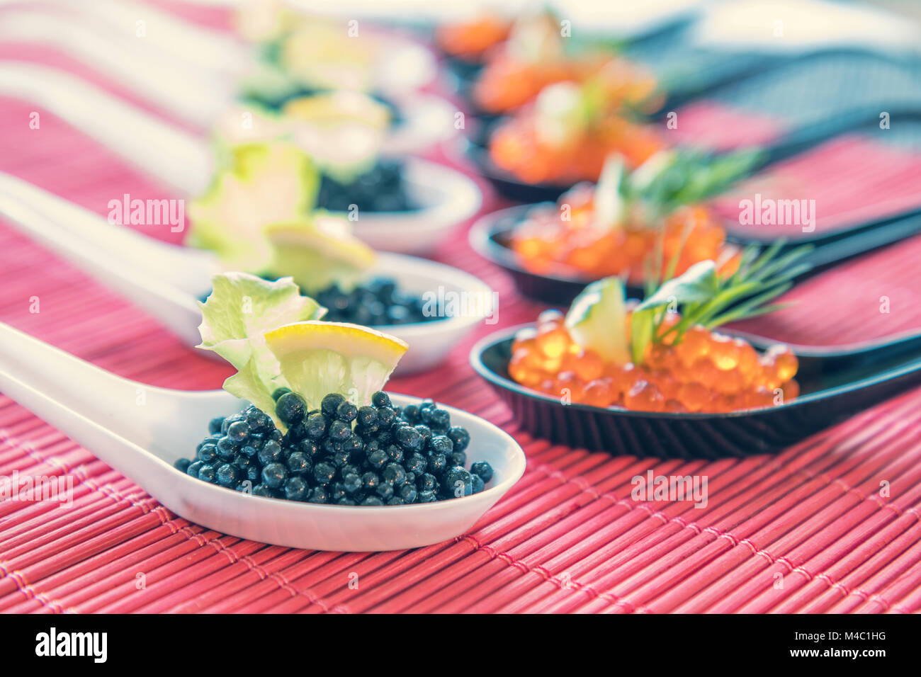 Rosso e nero pesci Caviale in bianco, nero cucchiai Foto Stock