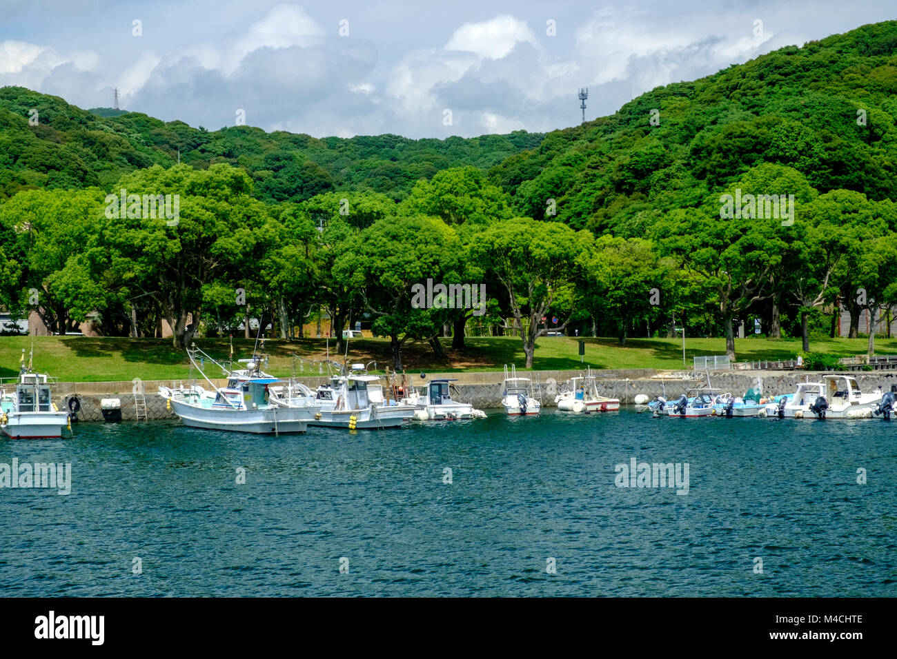 Porto Saikai, Sasebo, di Nagasaki, Giappone. Svuotare barche ormeggiate nell'acqua. Alberi, arbusti e sulle montagne sullo sfondo. Foto Stock