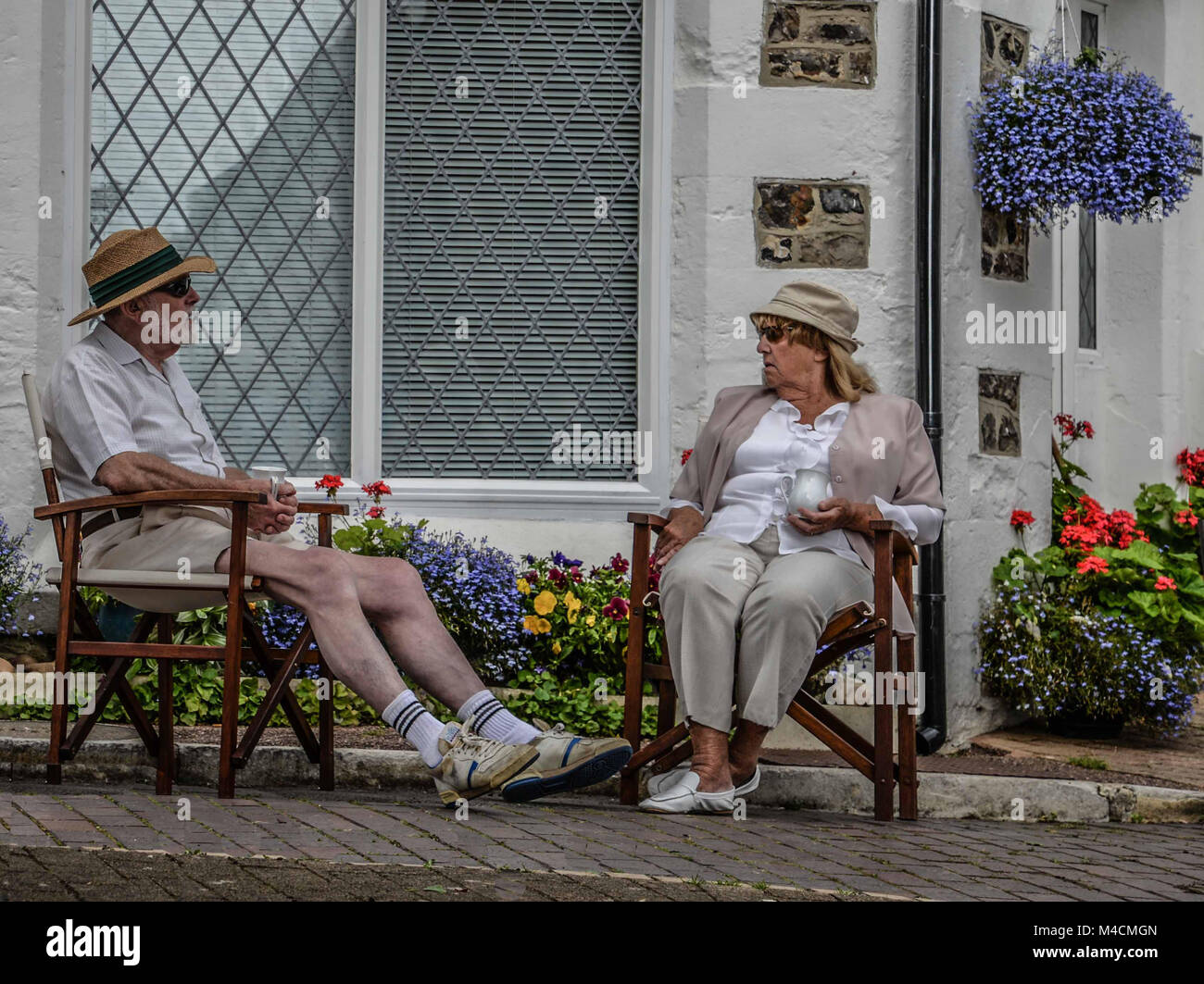 Una coppia di anziani in rilassanti sedie aventi una chat, birra, Dorset, England, Regno Unito Foto Stock