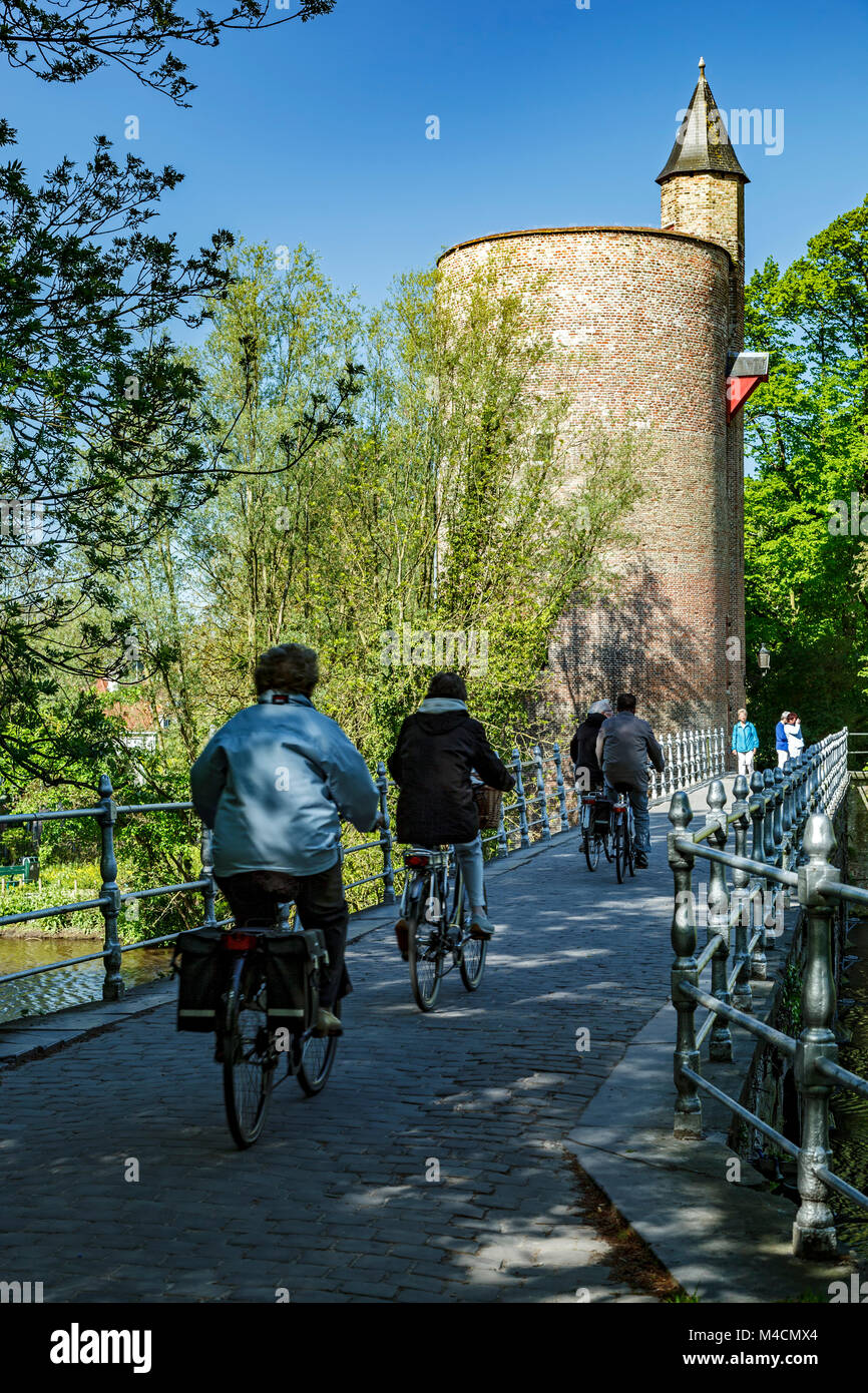 Torre e ciclisti attraversando il ponte, parco Minnewater, Bruges, Belgio Foto Stock