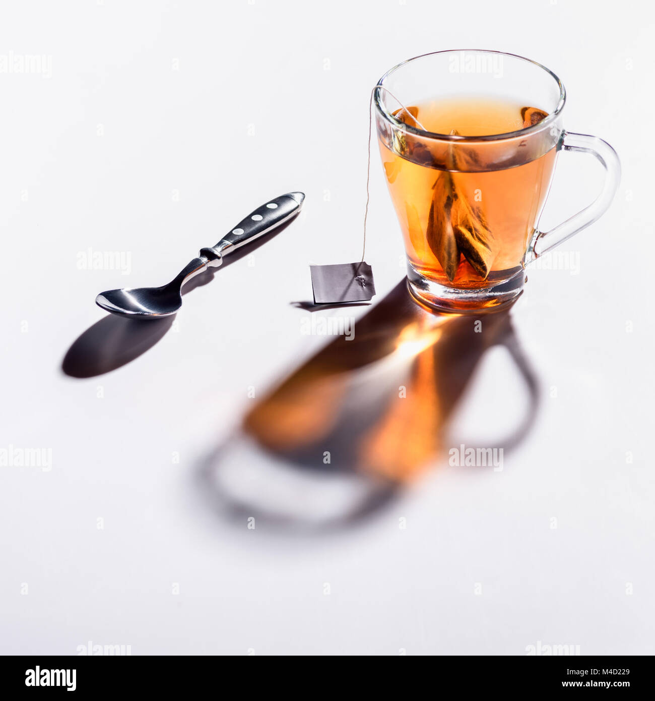 Bicchiere di vetro di tè nero e il cucchiaio sul tavolo Foto Stock