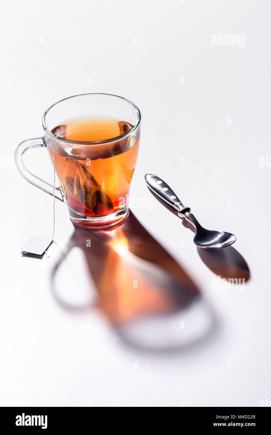 Bicchiere di vetro di tè nero e il cucchiaio sul tavolo Foto Stock