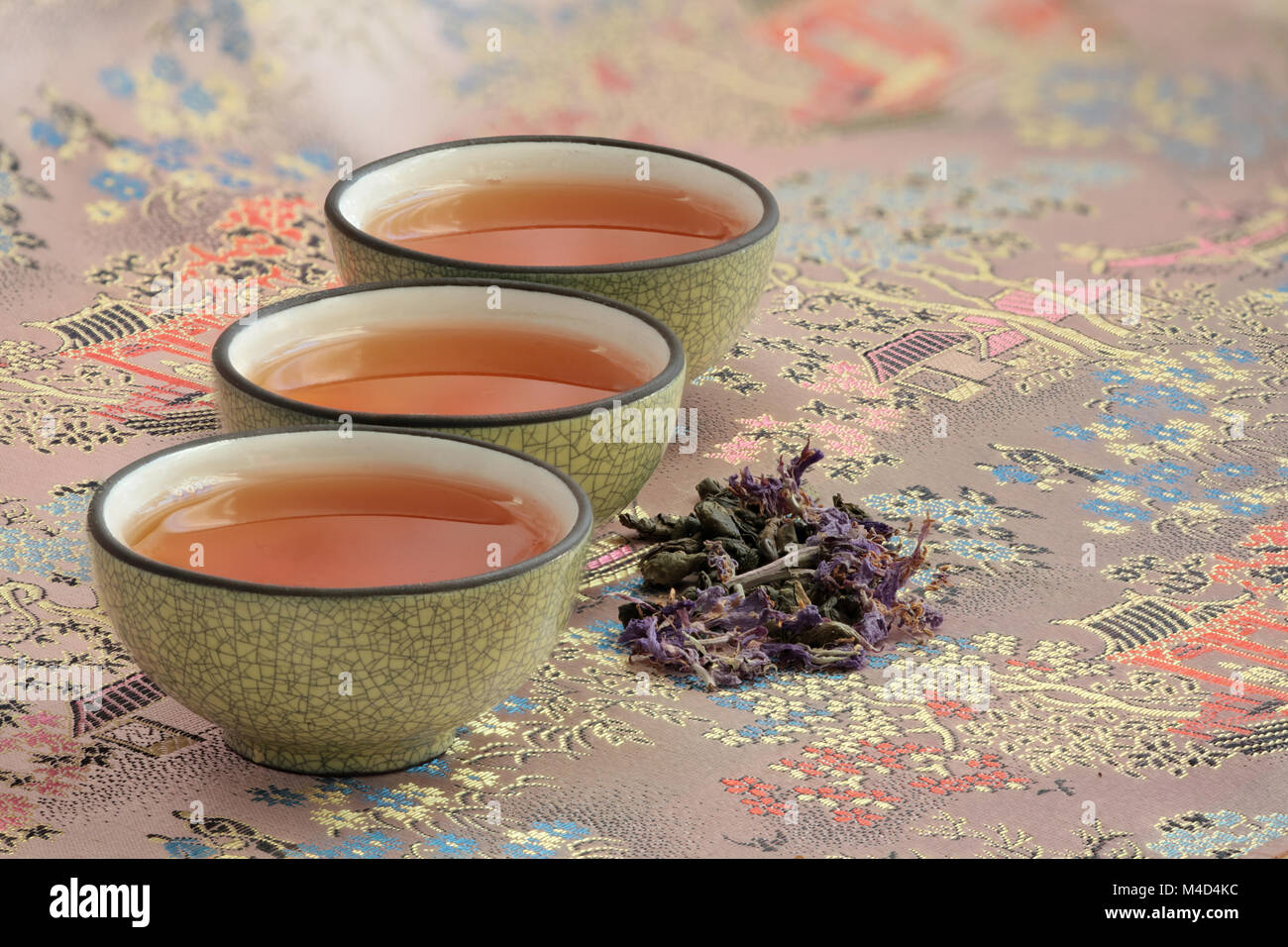 Tre tazze riempite con tè su una bella tovaglia Foto Stock