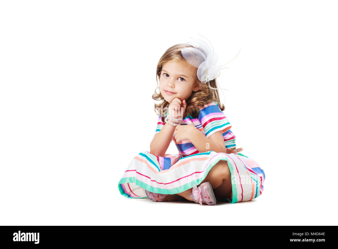 Piccolo felice ragazza seduta sul pavimento, isolato su bianco Foto Stock