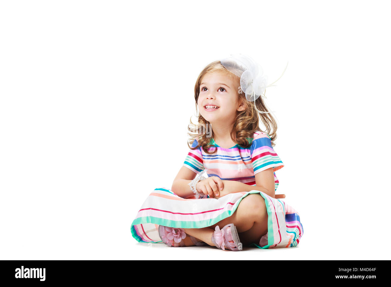 Piccolo felice ragazza seduta sul pavimento, isolato su bianco Foto Stock