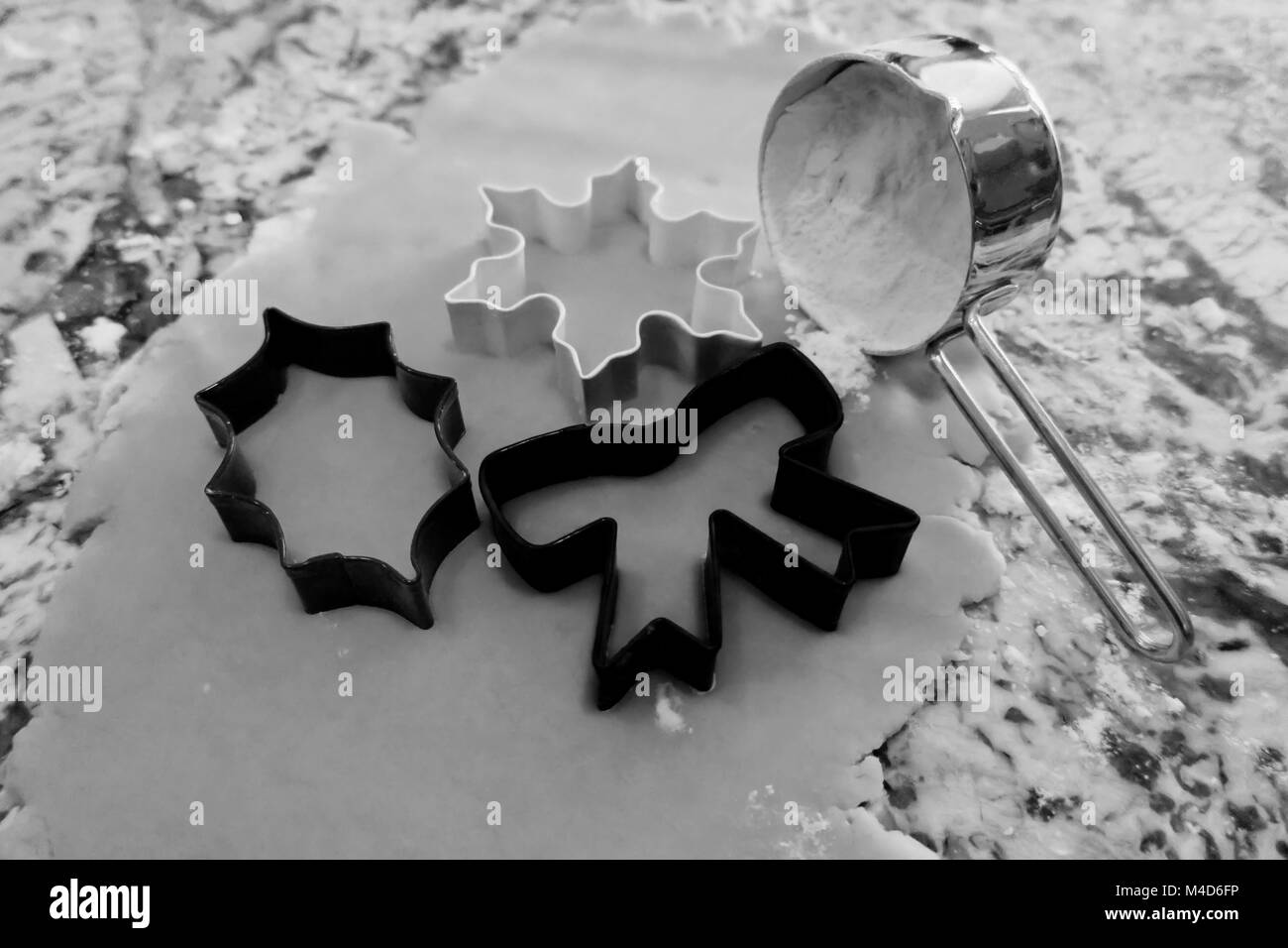 Tre natale cookie cutters accanto a farina in bianco e nero. Foto Stock