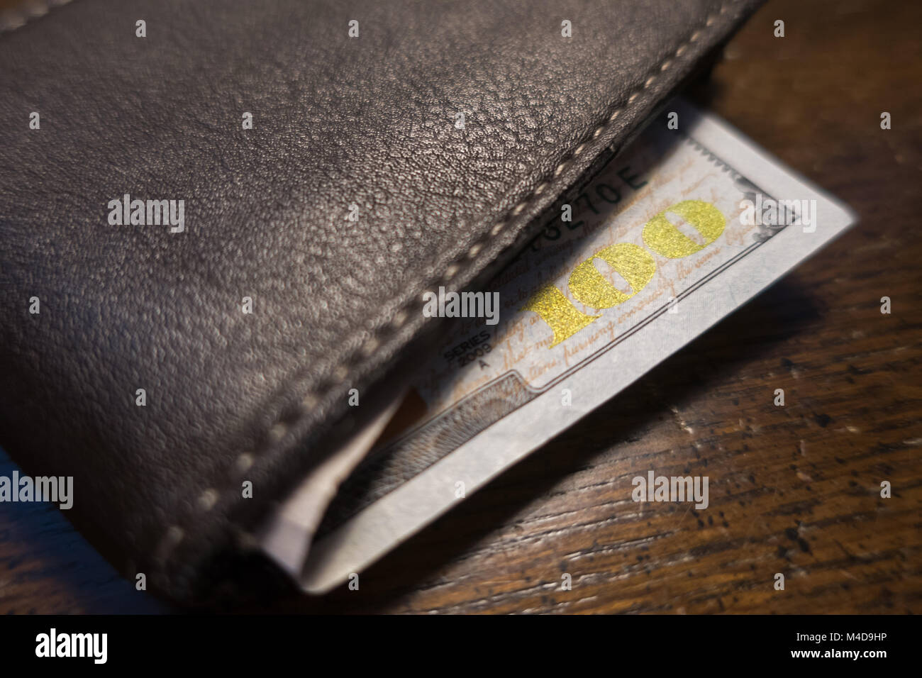 Un centinaio di dollari bloccata al di fuori di un marrone pelle bi fold wallet. Foto Stock