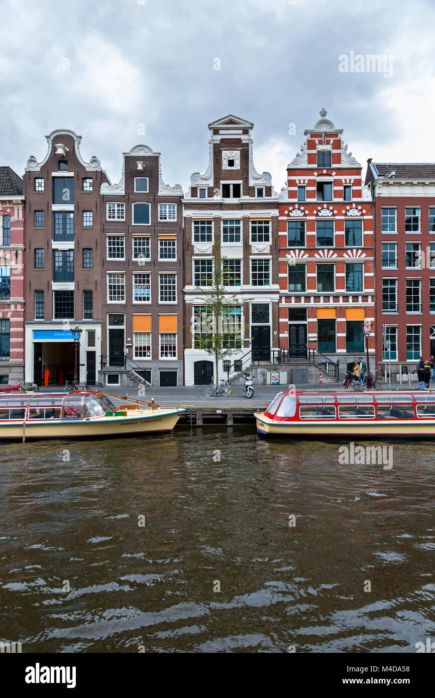 Strette colorate case a schiera con spazio di vendita al di sotto del canale di Amsterdam, Paesi Bassi. Tourboats sul canale. Foto Stock