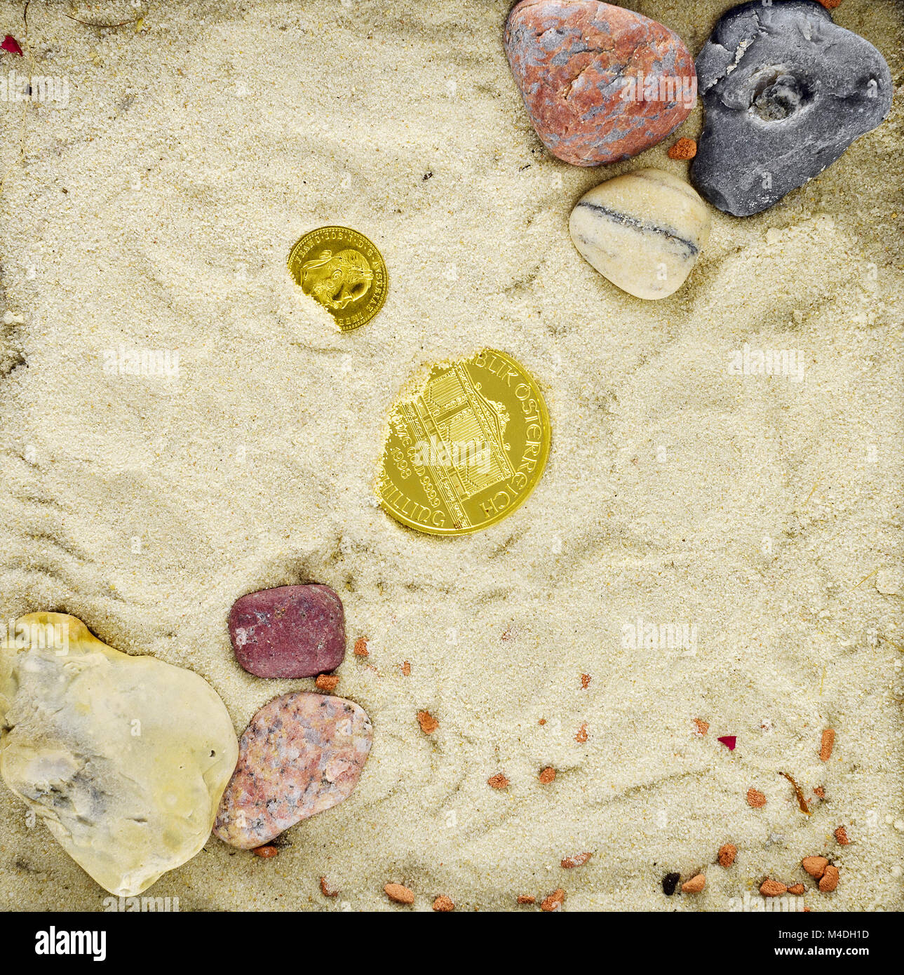 Monete d oro con sabbia e pietre Foto Stock