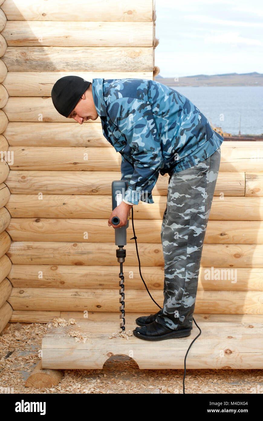 Carpenter trapani un log sulla costruzione di log cabin Foto Stock