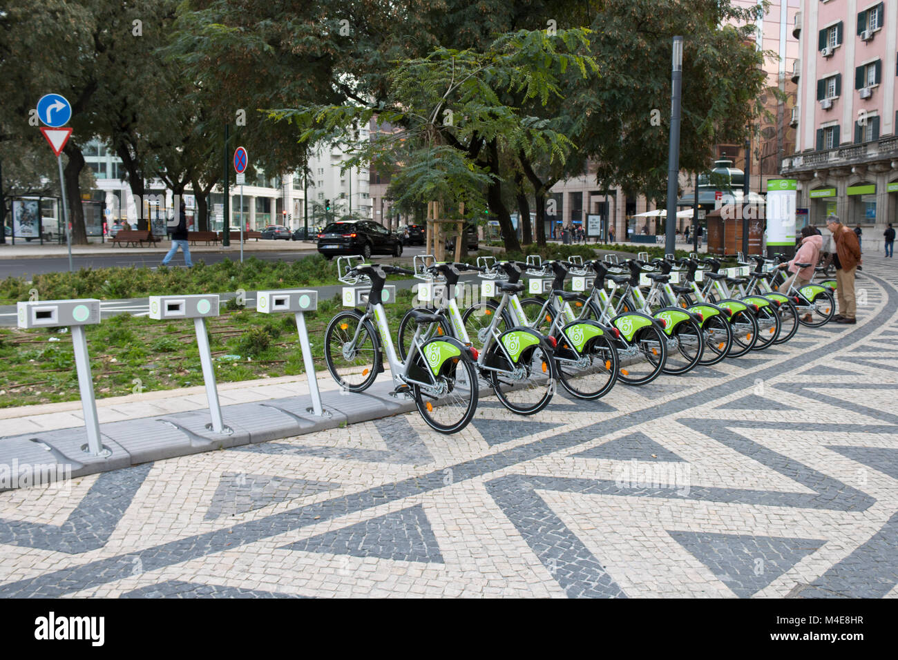 Lisbona, Portogallo: Noleggio di biciclette elettriche parcheggiate in città. Una coppia che prova una bicicletta Foto Stock