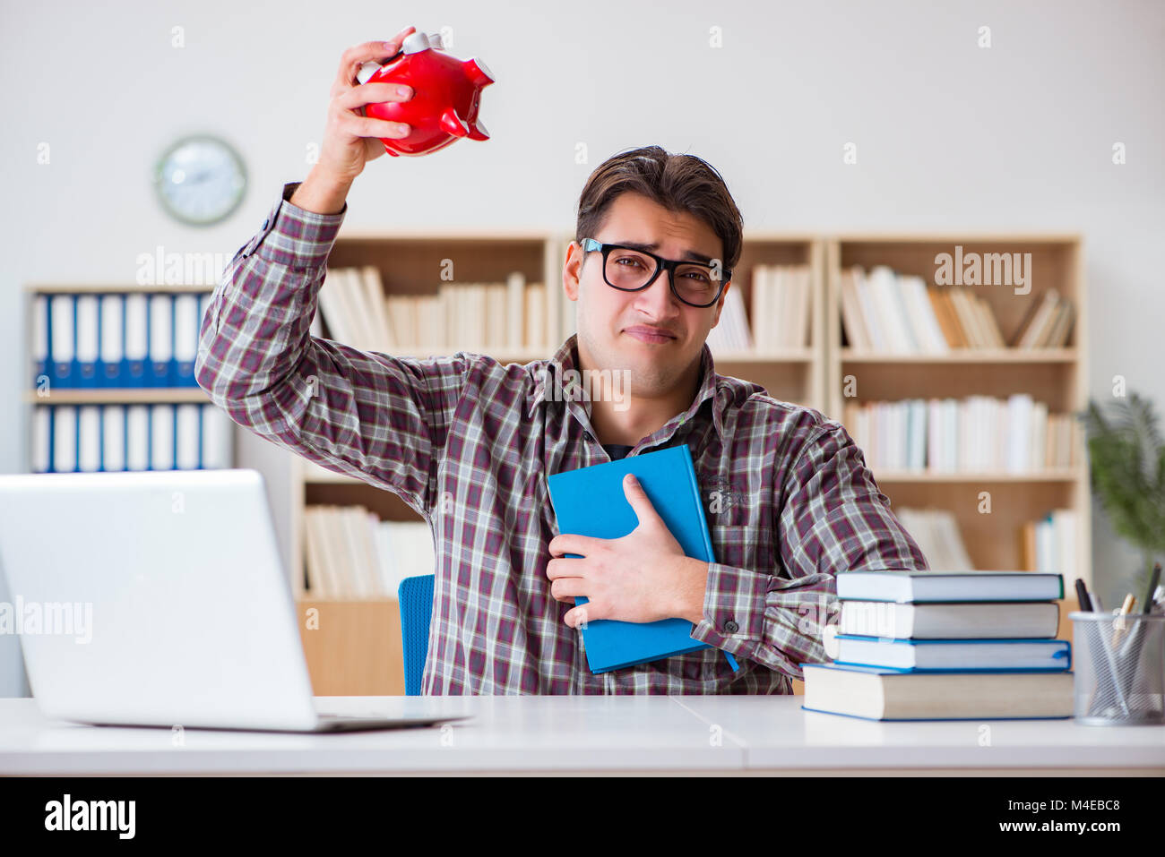 Rottura dello studente piggybank per pagare le tasse di iscrizione Foto Stock
