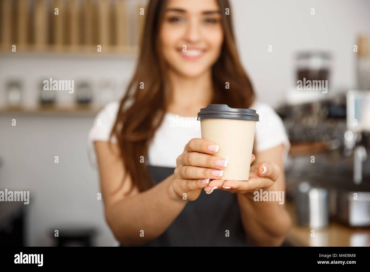 Caffè il concetto di Business - bella signora caucasica sorridente a offerte fotocamera monouso per tenere lontano il caffè caldo presso il moderno coffee shop Foto Stock