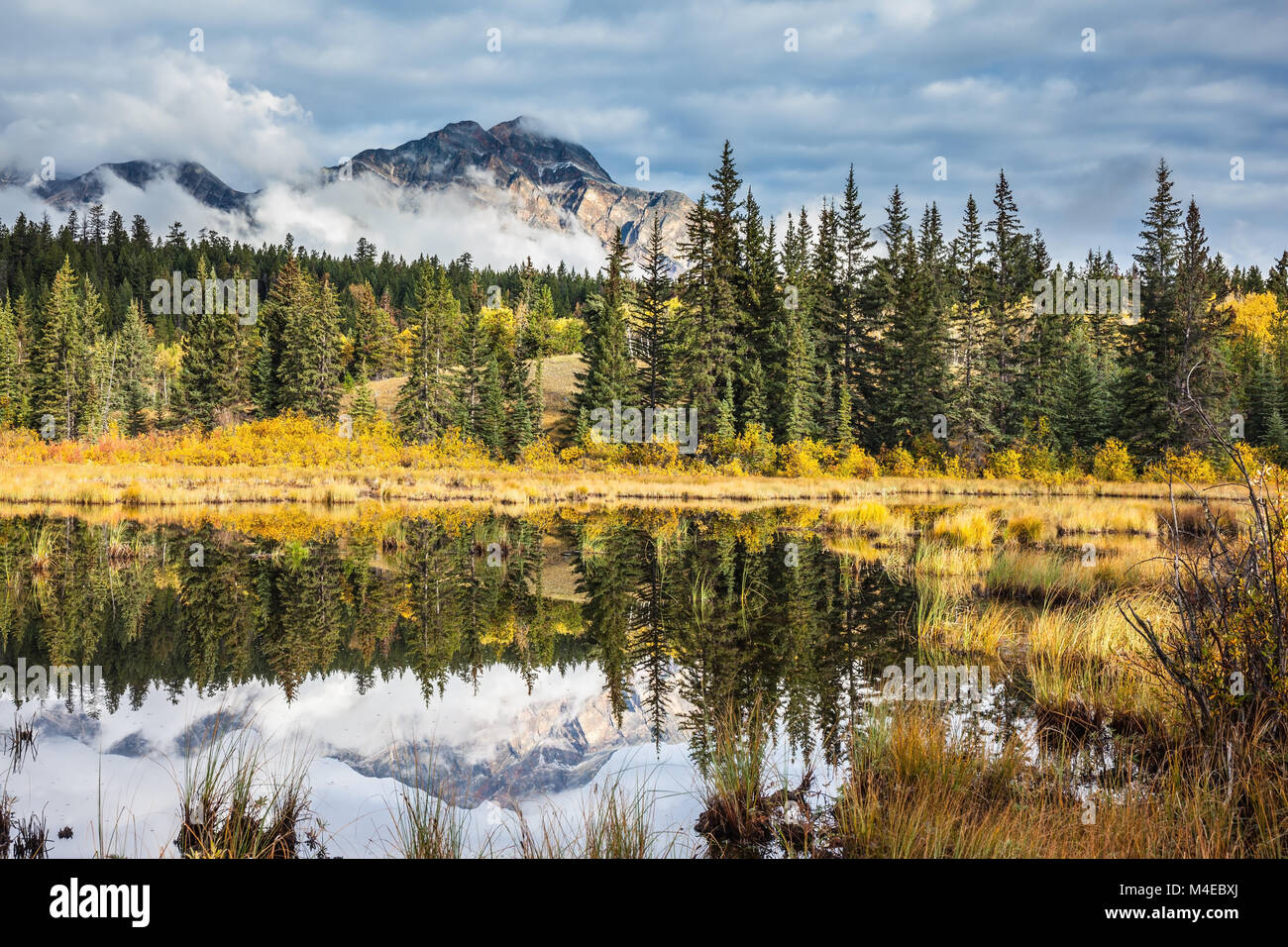 Le montagne e le nuvole sono riflesse in acqua fredda Foto Stock