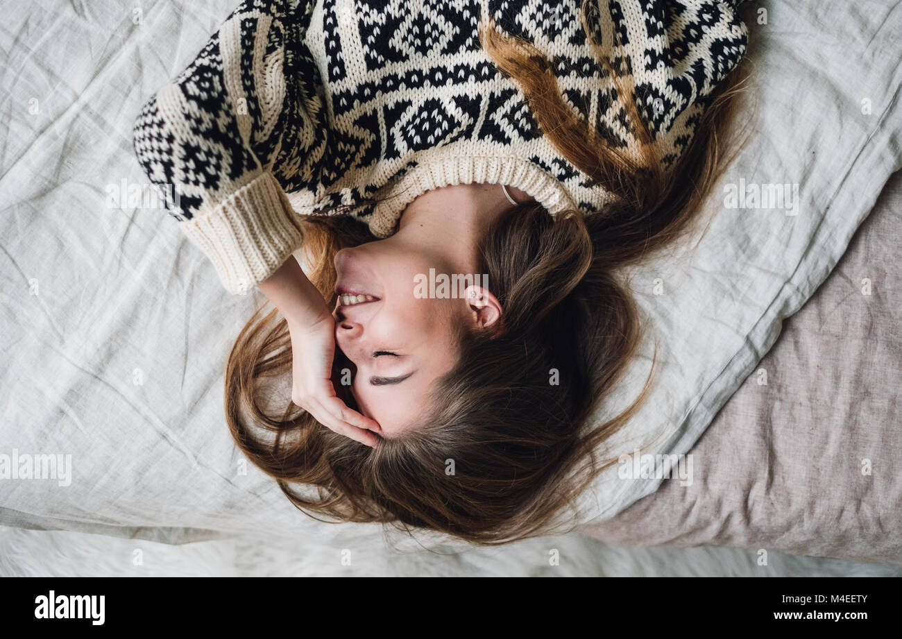 Donna sorridente giacente sul letto Foto Stock