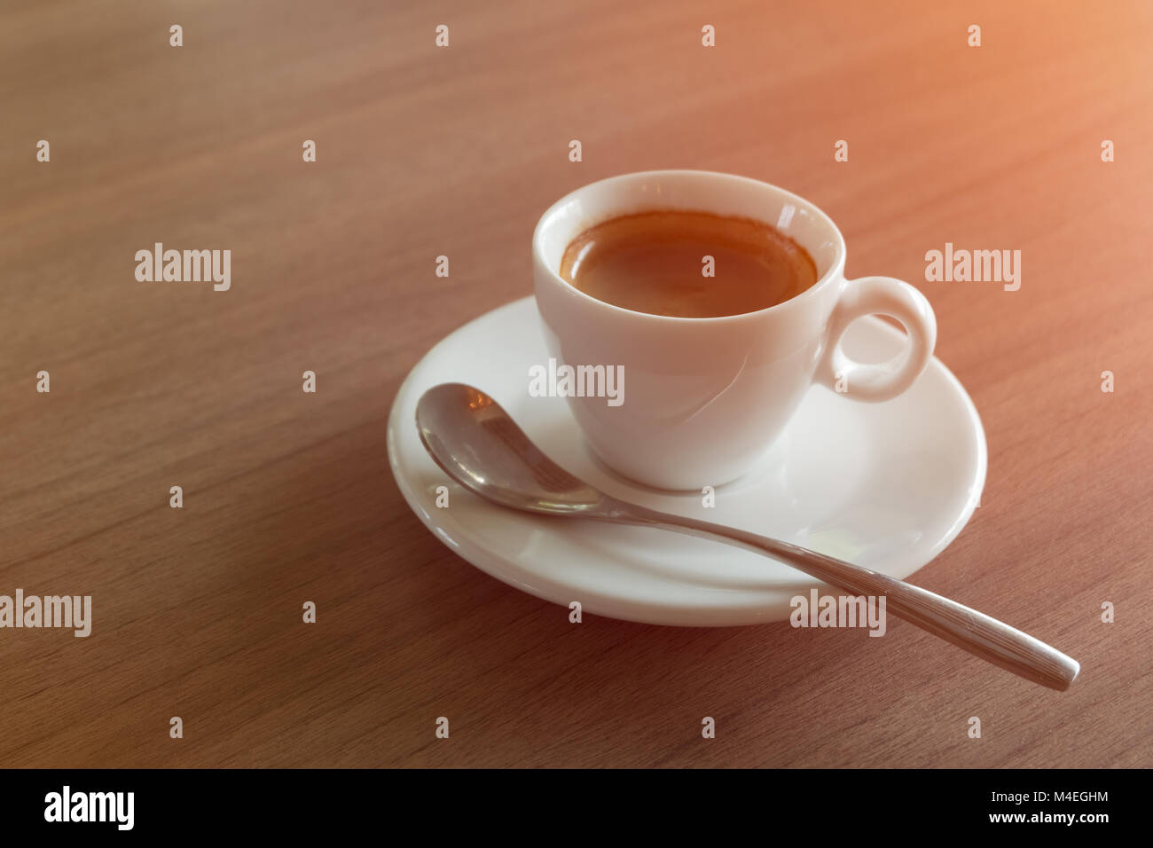 Caffè Espresso tazza bianca sul tavolo con illuminazione arancio. Foto Stock