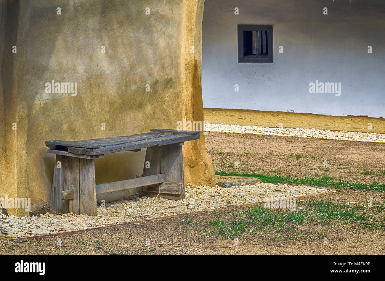 Vecchia panca di legno prima di un muro di fango Foto Stock