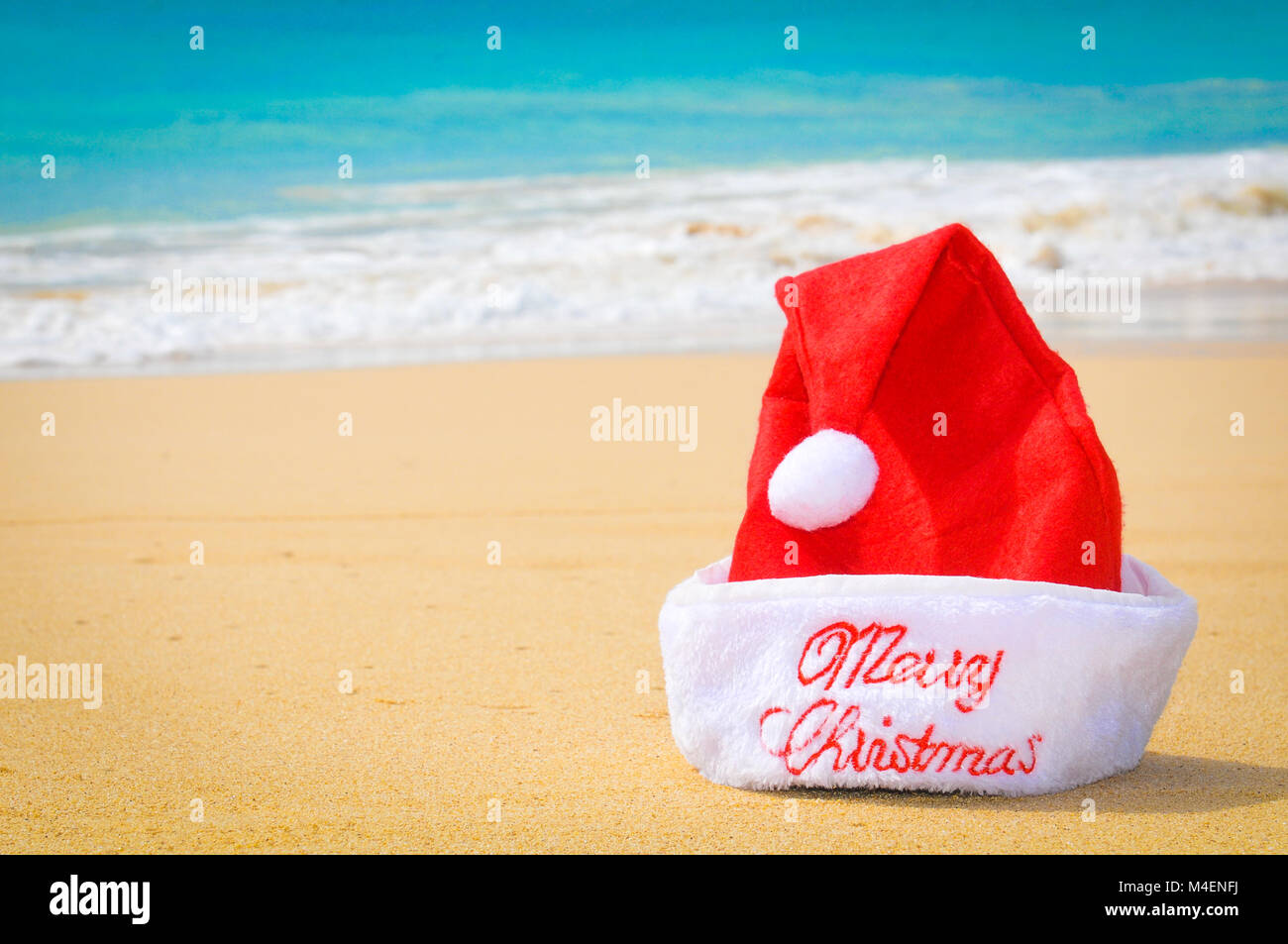 Di viaggio o di vacanza concetto con un dettaglio di una Santa Red Hat su una spiaggia esotica Foto Stock