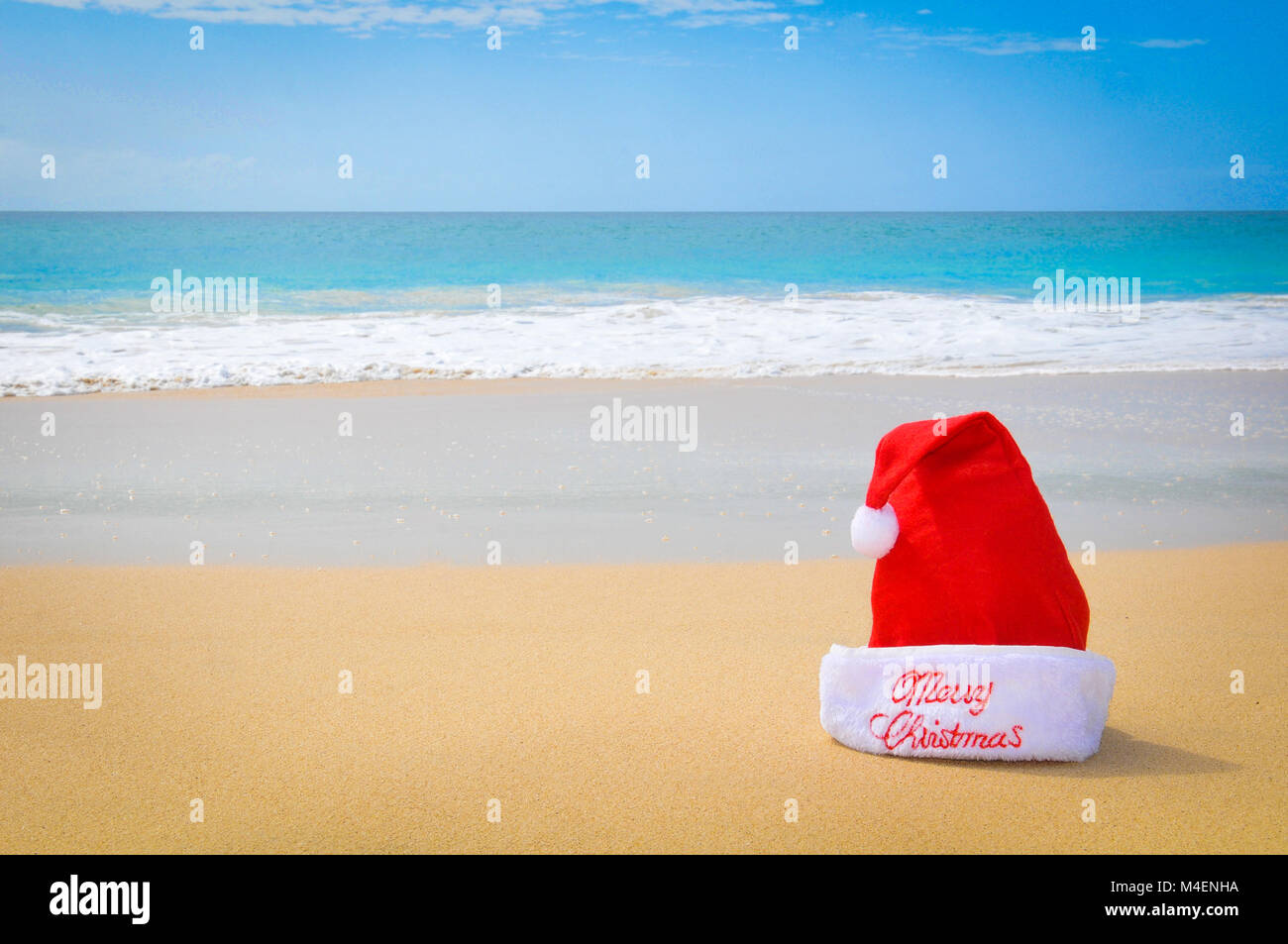 Di viaggio o di vacanza concetto con un dettaglio di una Santa Red Hat su una spiaggia esotica Foto Stock