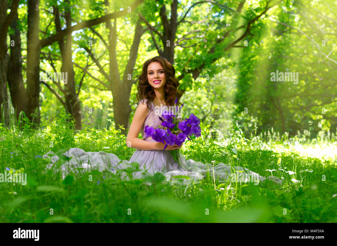 Giovane Donna con fiori nella foresta (con sunray ver) Foto Stock