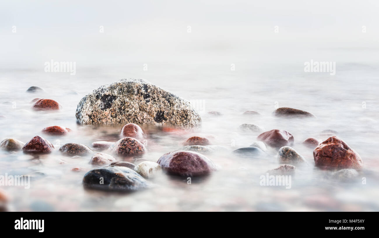 Forme d'onda colpendo in rocce sul mare Foto Stock