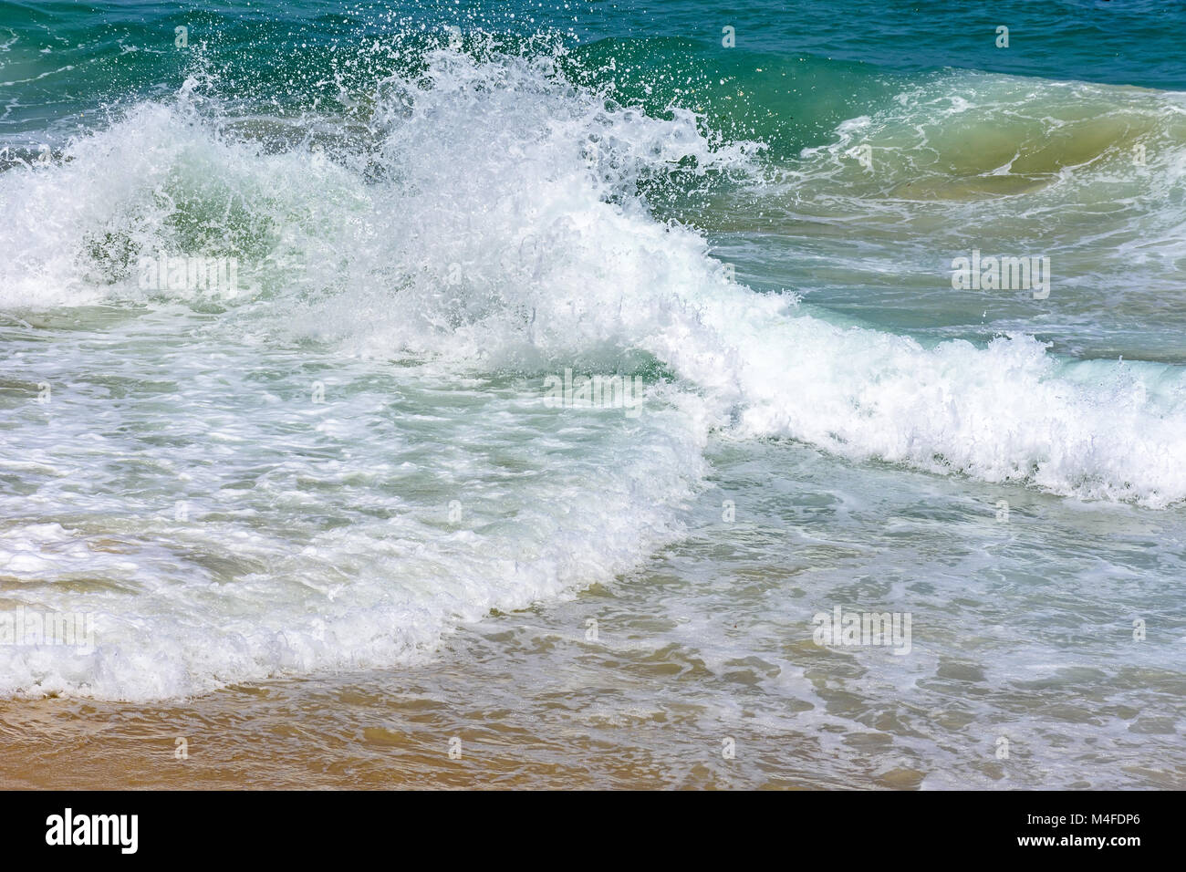 Onde che si infrangono sulla spiaggia Foto Stock