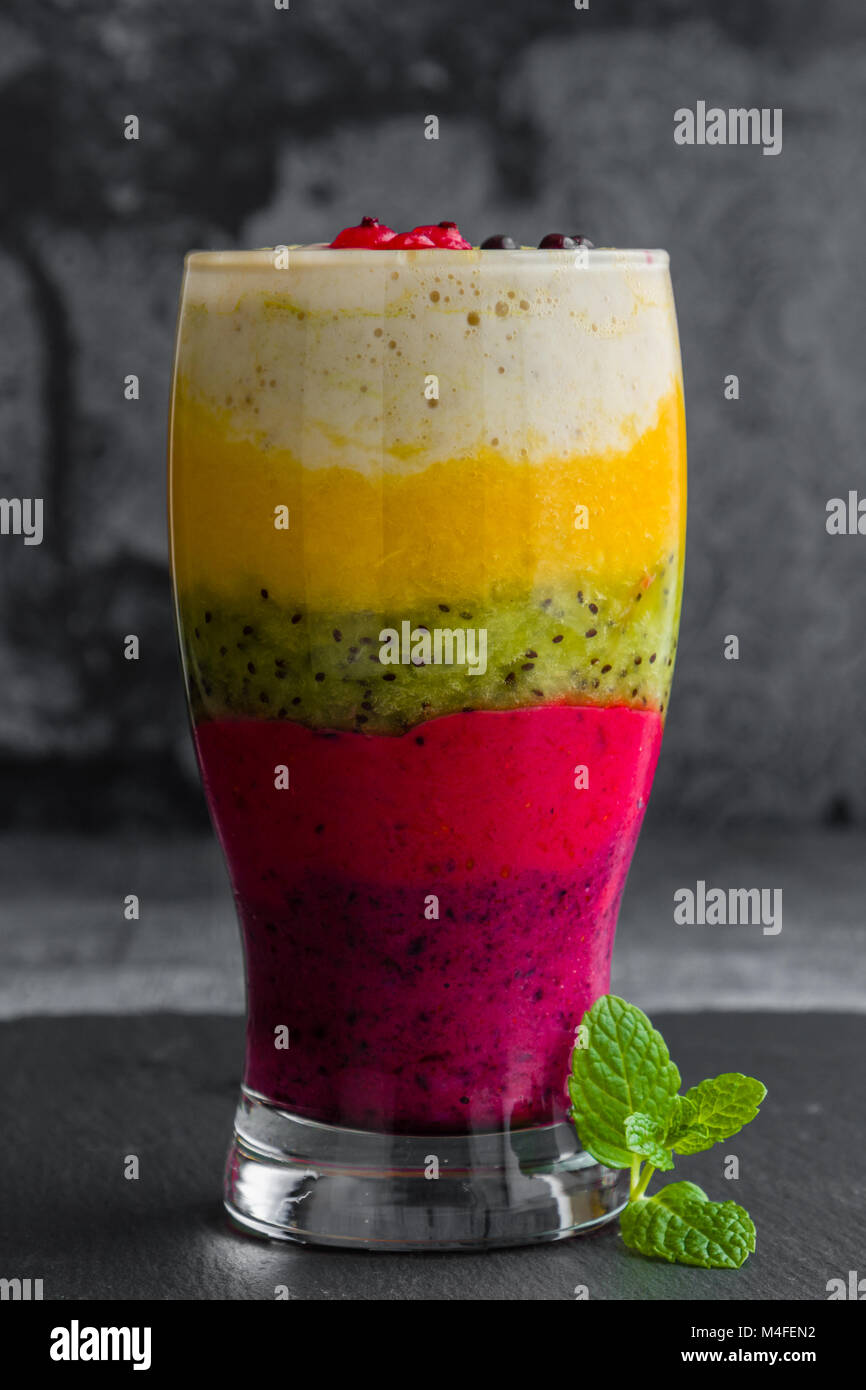 Frullato colorato fatto di frutti diversi stratificato in un bicchiere Foto Stock