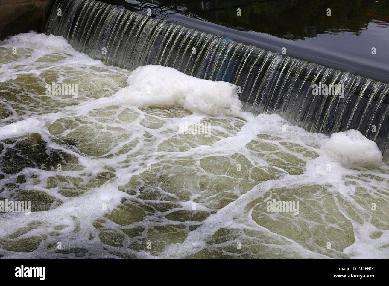 Sporco fiume inquinato di acqua, cadendo dal jetty mole rift e la formazione di schiuma, ad alto angolo di visualizzazione diagonale Foto Stock