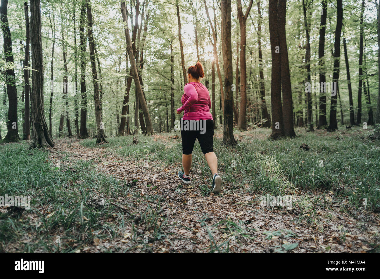 Vista posteriore di una donna sovrappeso cercando di mantenersi in forma e fare jogging. Foto Stock