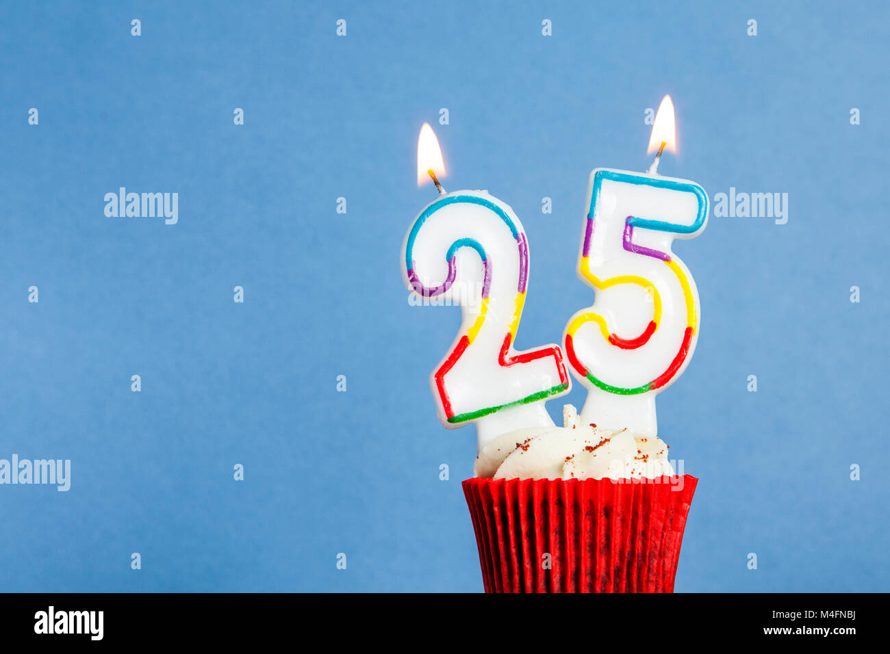 Numero 25 compleanno candela in una tortina contro uno sfondo blu Foto Stock