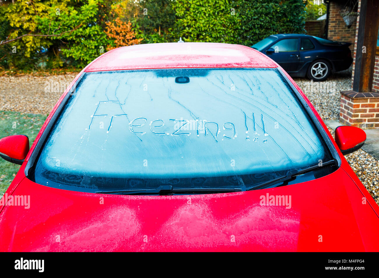 Woking, Surrey. Xvi Feb, 2018. Regno Unito: Meteo gelo notturno di temperature si formano uno strato di brina sulle finestre di un rosso macchina parcheggiata fuori per tutta la notte a basse temperature. La parola "congelamento" è scritto nel ghiaccio sul parabrezza congelati. Credito: Graham Prentice/Alamy Live News Foto Stock