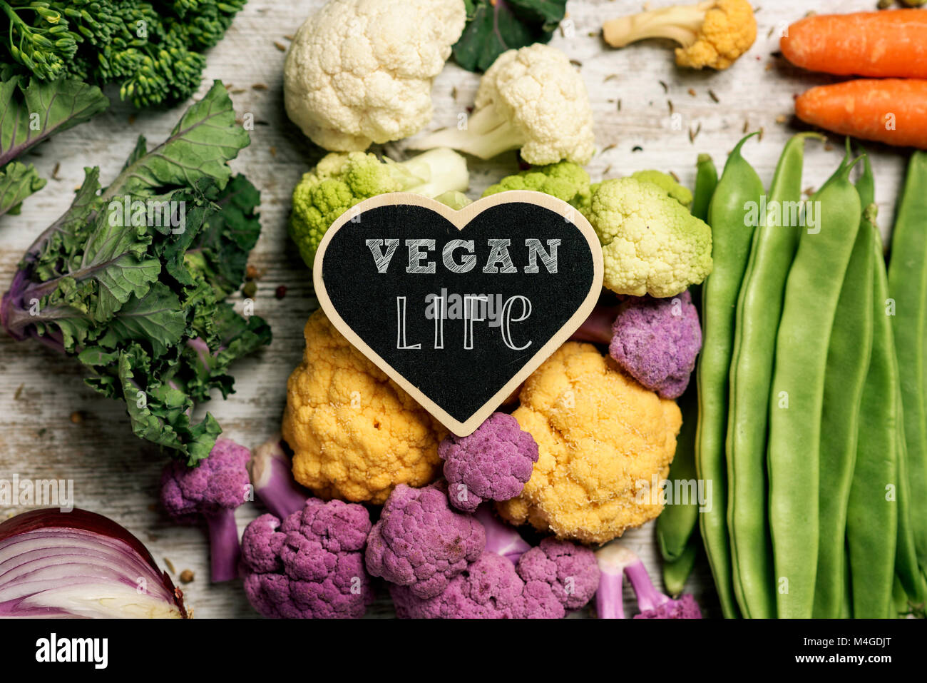 A heart-shaped cartello con il testo vita vegana collocato su una pila di alcune diverse verdure crude, come i cavolfiori di diversi colori, broccoli Foto Stock