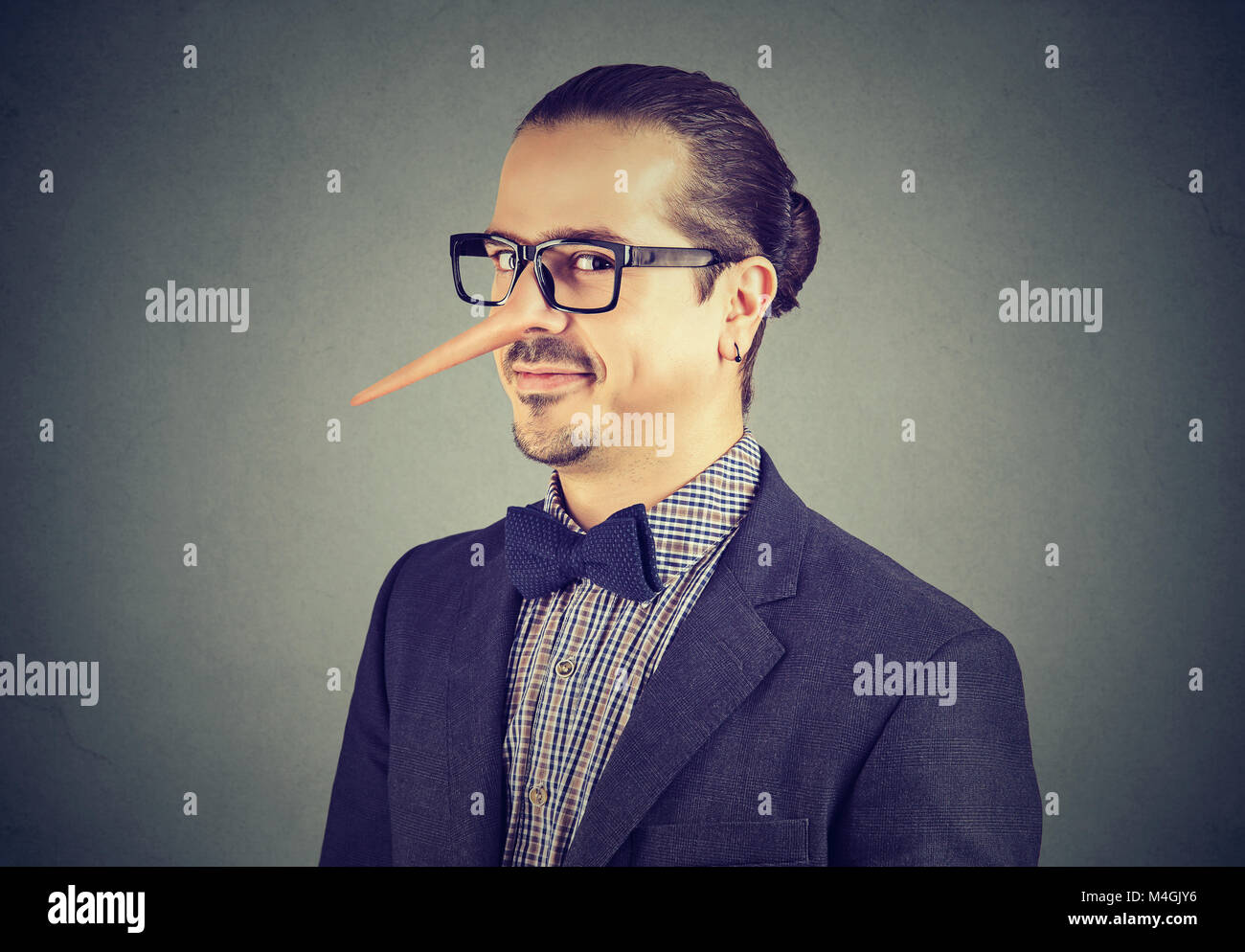 Uomo d affari con il naso lungo isolato su sfondo grigio. Concetto bugiardo. Le emozioni umane, sentimenti. Foto Stock