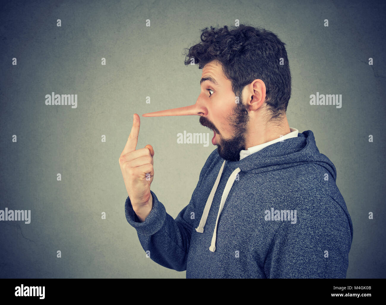 Uomo con il naso lungo isolato sul muro grigio Sfondo. Concetto bugiardo. Le emozioni umane, sentimenti. Foto Stock
