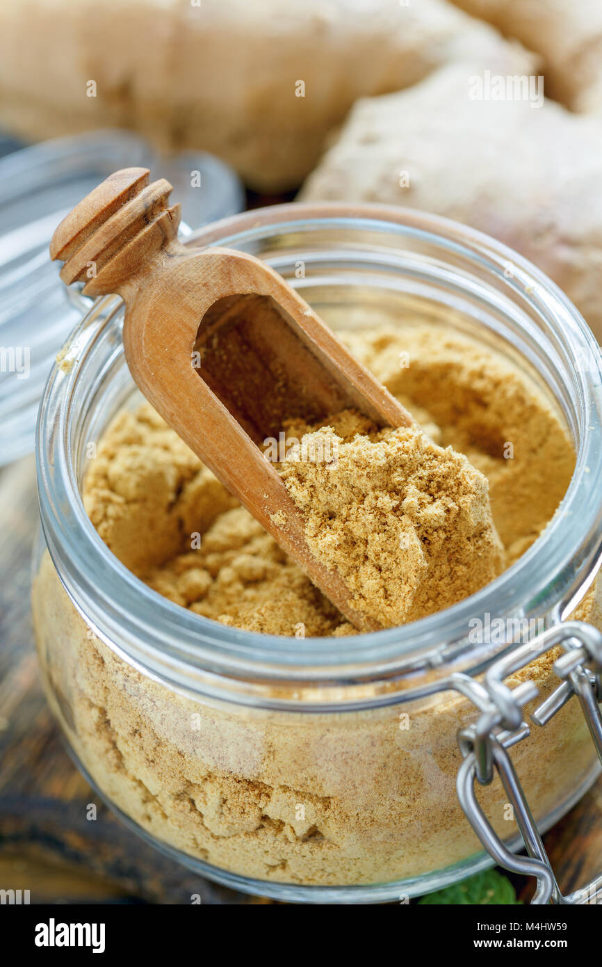 Lo zenzero in polvere e il cucchiaio di legno in un vasetto di vetro. Foto Stock