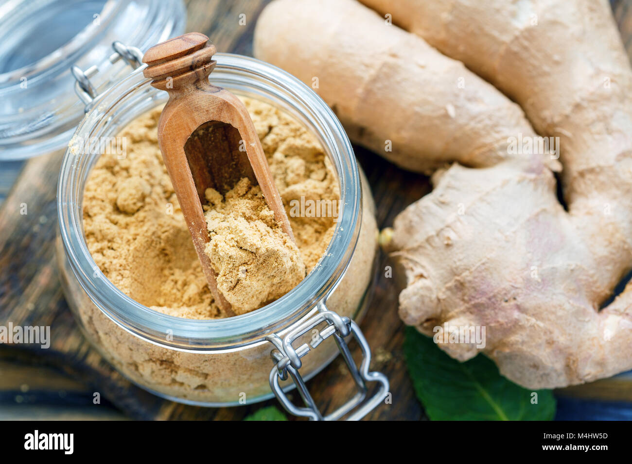 Cucchiaio di legno e lo zenzero in polvere in un recipiente di vetro. Foto Stock