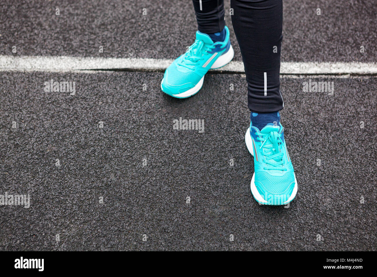 La donna per le gambe in blu con scarpe da corsa in piedi su asfalto Foto  stock - Alamy