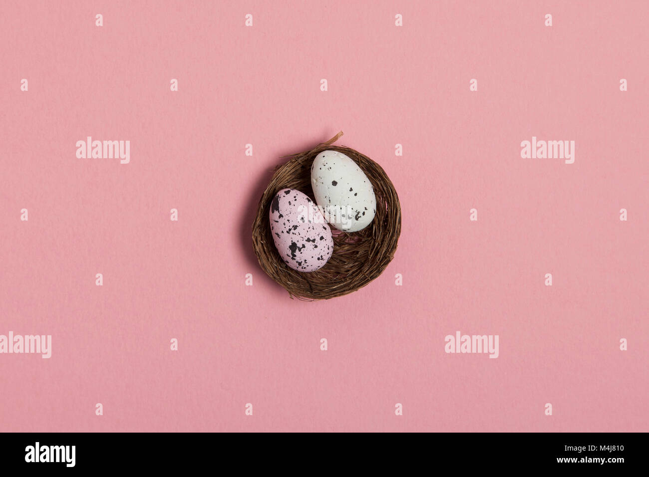 Uova di Pasqua in un nido su un pastello sfondo rosa Foto Stock