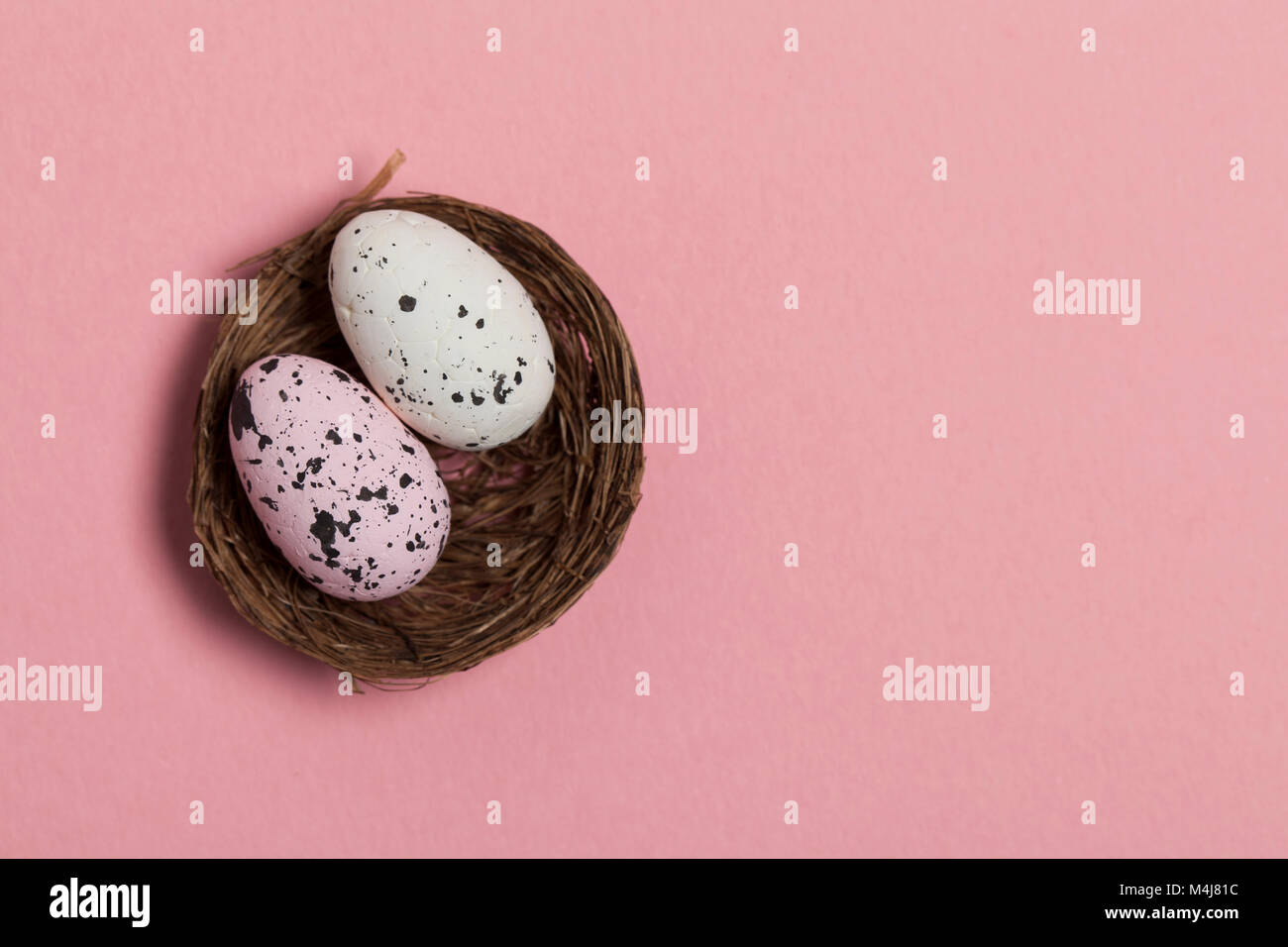 Uova di Pasqua in un nido su un pastello sfondo rosa Foto Stock