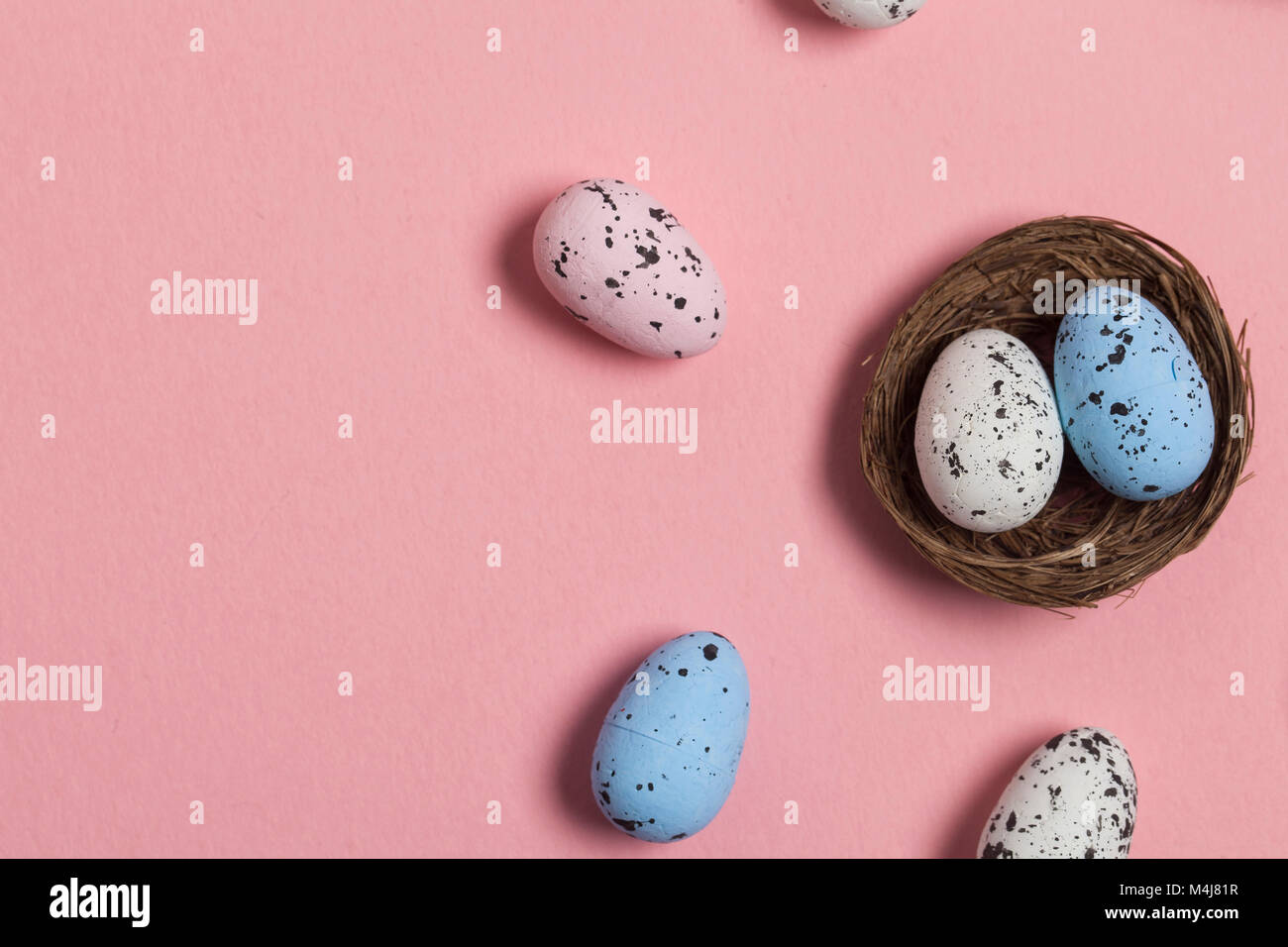 Uova di Pasqua in un nido su un pastello sfondo rosa Foto Stock