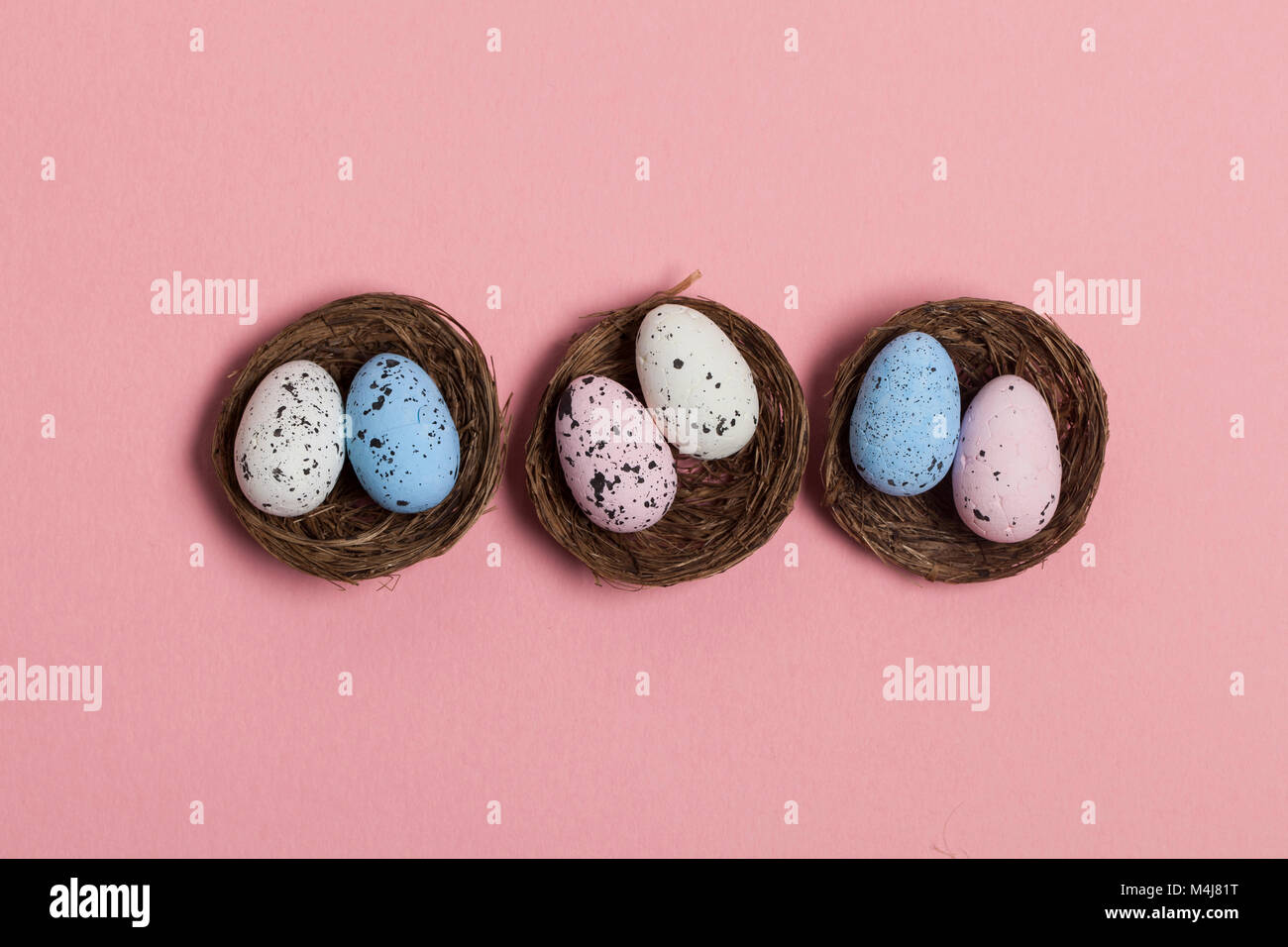 Uova di Pasqua in un nido su un pastello sfondo rosa Foto Stock