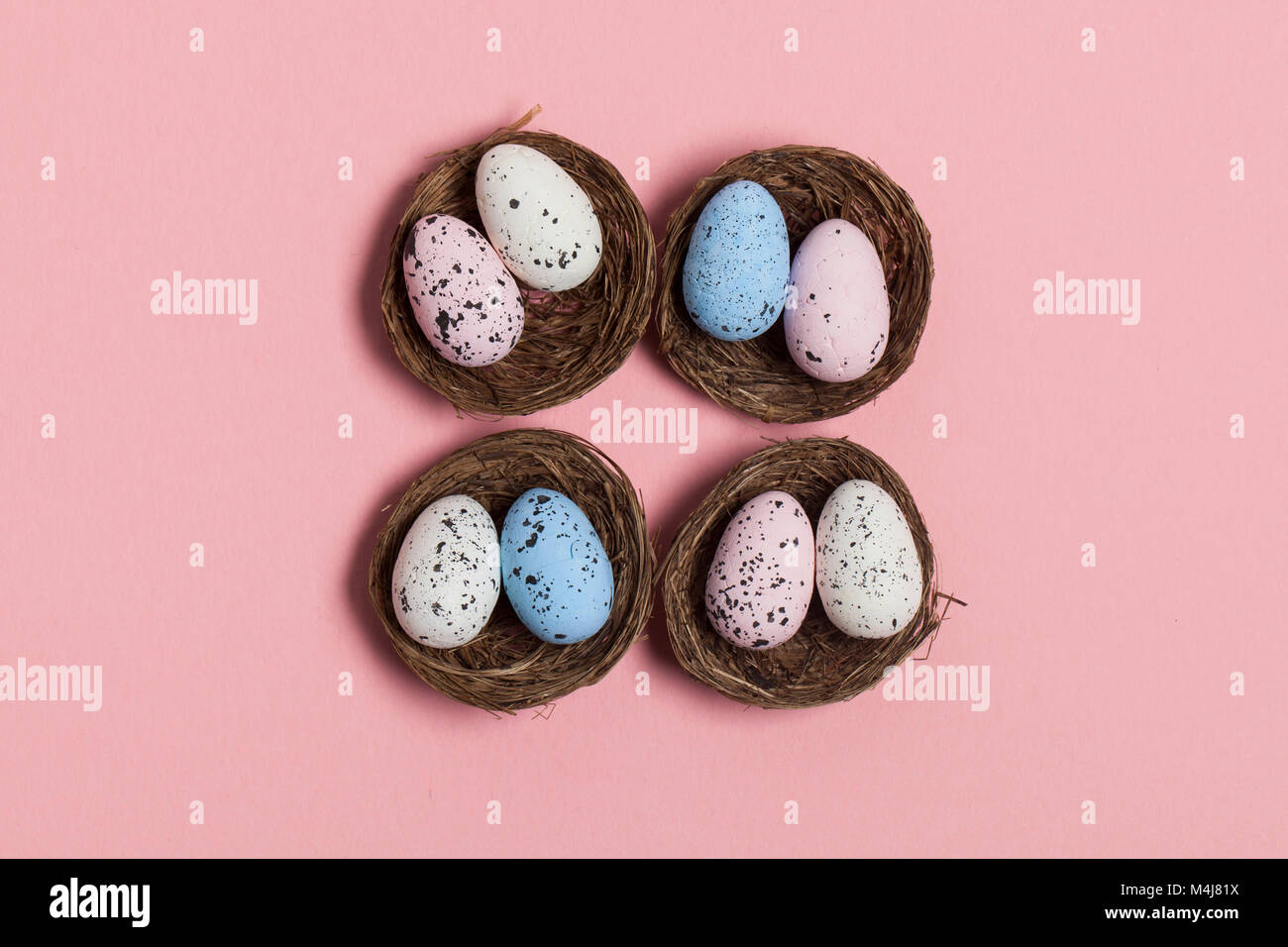 Uova di Pasqua in un nido su un pastello sfondo rosa Foto Stock