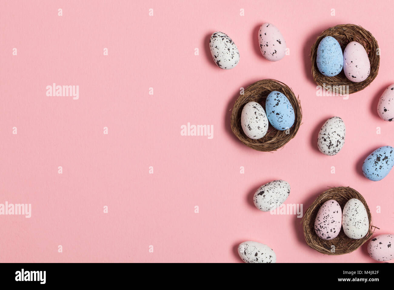 Uova di Pasqua in un nido su un pastello sfondo rosa Foto Stock